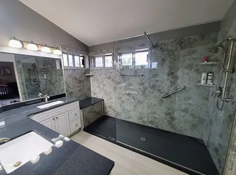 Green Marble Walk-In Shower — oversized walk-in shower in green marble-look panels with a dark base, bench seat, dual grab bars and clear glass wall, installed by Revive Bath Solutions in Tyler, TX