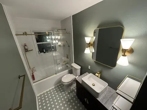 Sage & Brass Guest Bath — guest bathroom refresh with sage green walls, brushed brass fixtures, a vessel sink vanity, patterned floor tile and glass tub enclosure, installed by Revive Bath Solutions in Flint, TX